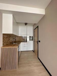 a kitchen with white cabinets and a wooden floor at Oostendelle in Ostend