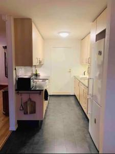 a white kitchen with a sink and a refrigerator at Miracle Tromso, cozy double bed private room in a shared apartment with Stunning Tromso Views in Tromsø +9 photos