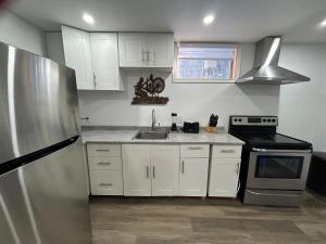 a kitchen with white cabinets and a stainless steel refrigerator at Bancroft VIBES l Sleep 7 l BBQ I FIRE PIT in Bancroft