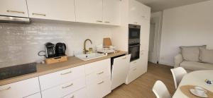 Domino 1 Superbement rénové - 2 chambres - Terrasse à 300m plage commerces في لو غراو دو روا: مطبخ بدولاب بيضاء ومغسلة وأريكة