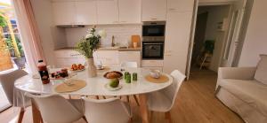 Domino 1 Superbement rénové - 2 chambres - Terrasse à 300m plage commerces في لو غراو دو روا: مطبخ مع طاولة بيضاء وكراسي بيضاء