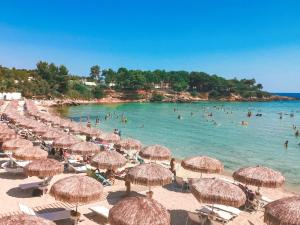 a beach with many straw umbrellas and people in the water at Il Rifugio delle Allodole in Leporano Marina