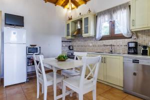 a kitchen with a white table and white chairs at Pefkos Cottage in Panormos Skopelos