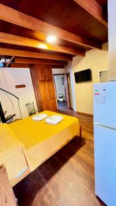 a yellow bed in a room with a refrigerator at Apart Hotel Géminis in Termas del Daymán