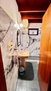 a bathroom with a sink and a marble wall at Apart Hotel Géminis in Termas del Daymán