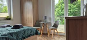 a bedroom with a bed and two chairs and a table at Karmelowy Zakątek in Darłowo