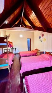 a room with three beds with pink sheets in it at Apart Hotel Géminis in Termas del Daymán