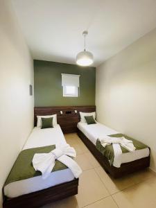 two beds in a room with green and white at Lafo Rooms in Elafonisi