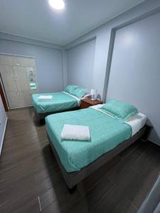 two beds in a hotel room with green sheets at Ravenala - Apartment Paracas in Paracas