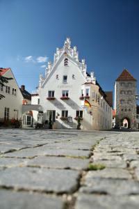 a large white building sitting on top of a stone road at Landhotel Weißer Hahn in Wemding