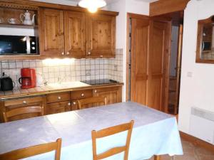 a kitchen with wooden cabinets and a table with chairs at Résidence Bergerie Des 3 Vallees D - Joli appartement 3 pièces 4 personnes situé sur Les Allues dans un quartier calme MAE-1971 in Les Allues