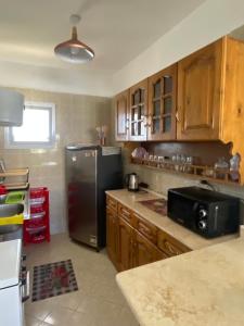 Una cocina con refrigerador negro y gabinetes de madera. en 52H Green leaves Village, families & couples only, en Dawwār Abū Duray‘ah ‘Abd al Karīm