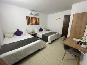 a hotel room with two beds and a desk at Aguacatala Hotel Boutique in Medellín