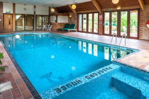 a large swimming pool with blue water in a building at Passford House Hotel in Lymington