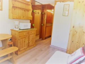 una piccola cucina con armadi in legno e forno a microonde di Résidence Le Palafour - Studio 2 personnes à Tignes au pied des pistes, des commerces, de l'ESF et de l'office du tourisme dans le quartier du lac. Appa MAE-2160 a Tignes