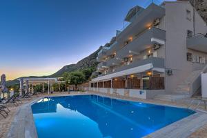 a hotel with a swimming pool in front of a building at Oceanis Rooms Apartments in Barbati