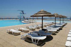 a row of chairs and umbrellas next to a pool at At the beach with a private garden in Carcavelos