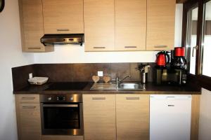 a kitchen with wooden cabinets and a stove and a sink at Chalet De La Tour - entièrement rénové et confortable MAE-3503 in Tignes