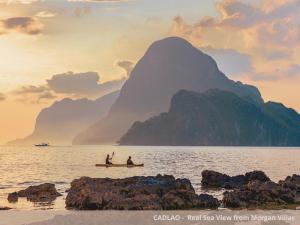 due persone su una barca in acqua con una montagna di Morgan Villas a El Nido