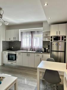 a kitchen with white cabinets and a table with chairs at Athena Apartment in Argostoli