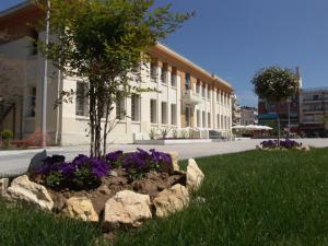 a tree in a flower bed in front of a building at Private Rooms in shared house in Thessaloniki