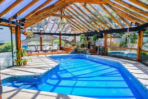 a swimming pool in a house with a glass roof at Hotel & Spa La Cheminée in San Martín de los Andes
