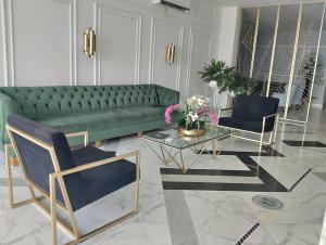 uma sala de estar com um sofá verde e duas cadeiras em Hotel OR Suite em Barranquilla
