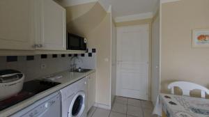 a kitchen with a sink and a washing machine at Maison résidence accès piscine gratuite in Talmont