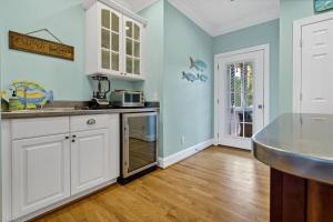 a kitchen with blue walls and white cabinets at Pompano Pool House in Edisto Island +25 photos