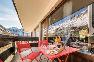 a red table and chairs on a balcony with a mountain view at Résidence Pistes - Studio 4 rénové - pied des pistes MAE-4648 in Tignes