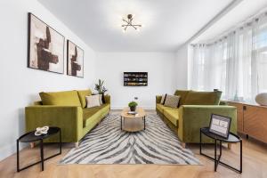 a living room with two green couches and a rug at Stylish 4 bedroom I extended stays I contractors in Harrow