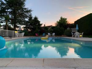 Una piscina con mesas y sillas en un patio. en Brit Hotel Dak Hotel, en Avallon