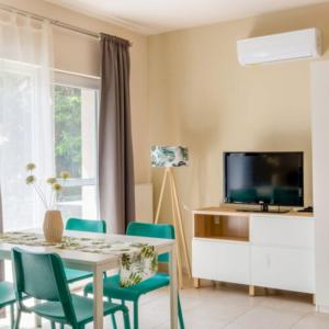 a living room with a table and chairs and a tv at Vas Villa in Siófok
