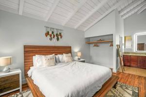 a bedroom with a large white bed with a wooden headboard at Contemporary 2-BR Condo AC & Scenic Views in PV in Princeville