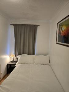 a white bed in a room with a window at MeadThames View in Thamesmead