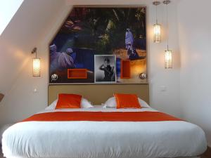 a bedroom with a large bed with orange pillows at Hôtel Mayet in Paris