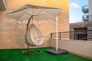 un parasol blanc et un hamac sur un balcon dans l'établissement Marina marassi, à Sīdī ‘Abd ar Raḩmān 2 autres photos
