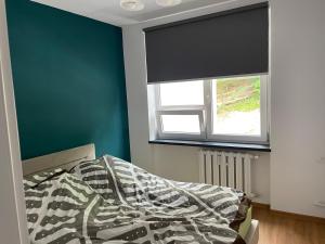 a bedroom with a bed with a green wall and a window at Kościuszki in Sanok