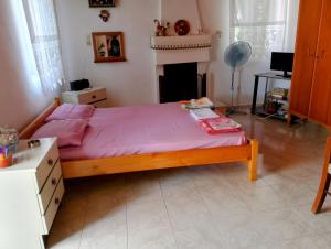 a bedroom with a bed with pink sheets and a fireplace at Trikeri traditional cozy house in Trikeri