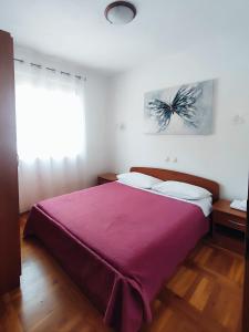 ein Schlafzimmer mit einem großen Bett und einer lila Decke in der Unterkunft Ravkin Apartments in Zadar