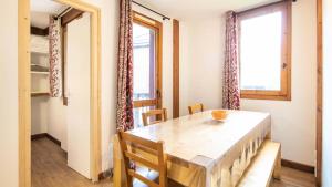 a dining room with a table and two windows at Le Chalet De Montchavin - Magnifique appartement rénové MAE-4234 in La Plagne Tarentaise +8 photos