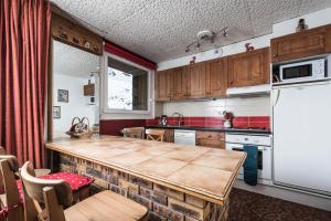 kuchnia ze stołem i białą lodówką w obiekcie Résidence Grande Balme I - Grand studio cabine avec balcon MAE-7664 w mieście Tignes
