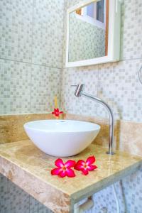 a white bowl sink on a counter with red flowers at Milano Hotel Pousada Canoa Quebrada in Canoa Quebrada