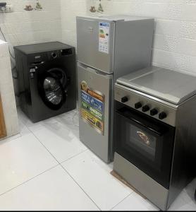 a kitchen with a stove and a washing machine at Zac Mbao appartement en face de la place in Mbaw