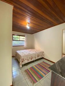 a bedroom with a bed and a window and a rug at Casa Tapovan in São Bento do Sapucaí