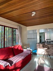 a living room with a red couch and a kitchen at Casa Tapovan in São Bento do Sapucaí +4 photos
