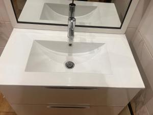 a white bathroom sink with a faucet and a mirror at Zac Mbao appartement en face de la place in Mbaw +18 photos