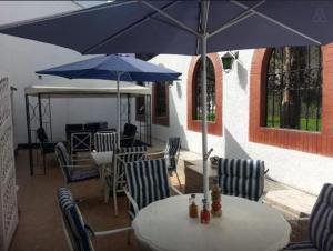 a table and chairs with a blue umbrella at B&B El Olivar in Lima