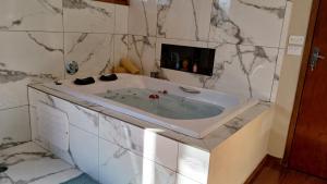 a bathroom with a tub with marble walls at Casa em São Francisco Xavier sp in São Francisco Xavier +19 photos