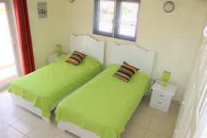 2 letti in una camera con lenzuola verdi di CAS IGUANA - Curacao - Villapark Fontein - Ferienhaus mit Pool a Fontein